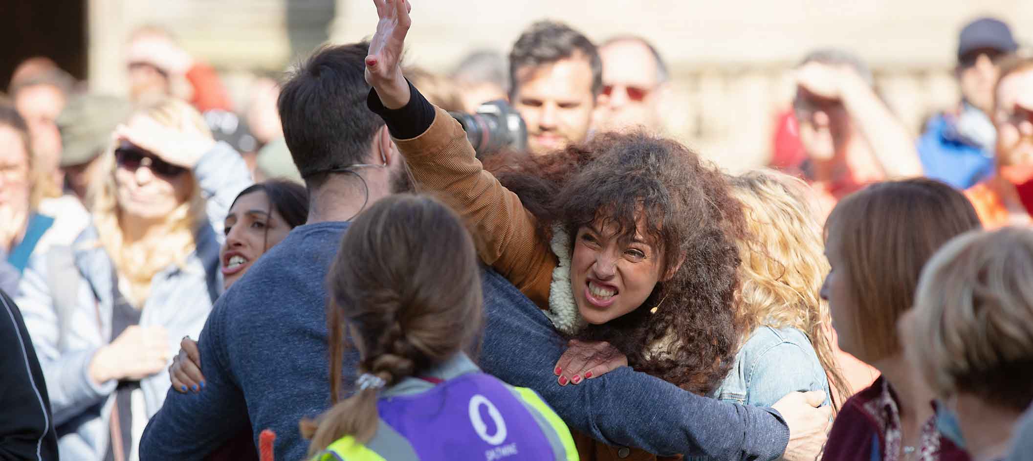 An actor fights to get past another actor in the midst of an audience as part of a Passion Play