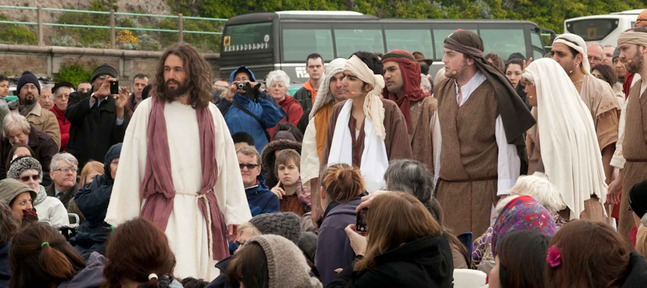 Actor portraying Jesus walks, with his disciples through an audience outside as part of the Brighton Passion Play